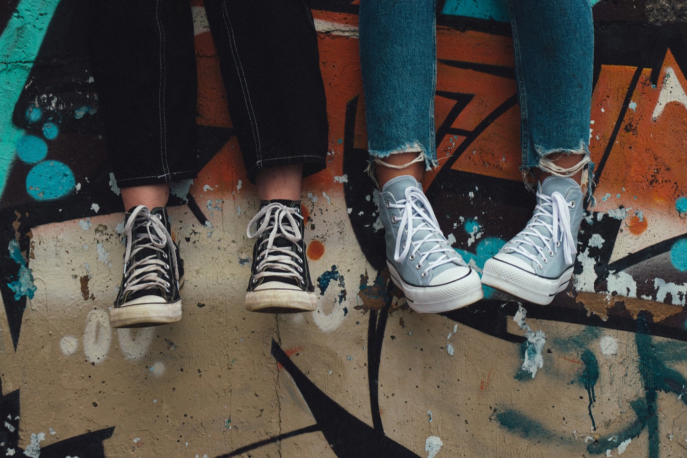 Two teenagers sitting on a wall covered in graffiti